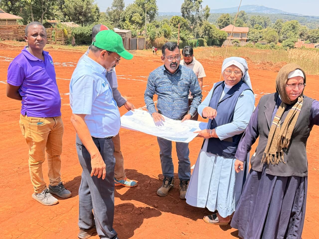 The team and Sisters reviewing building plans on the site